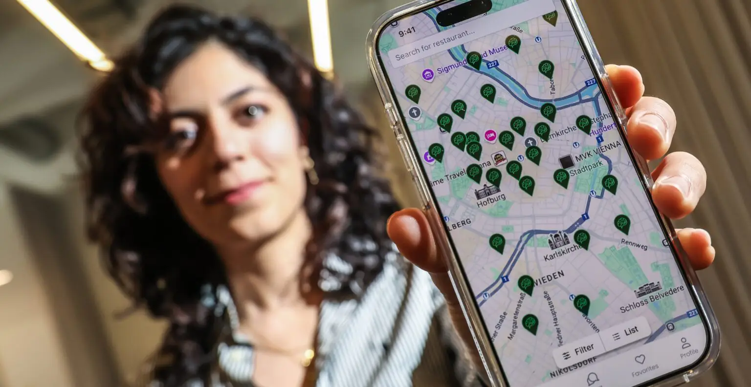 Eine HealthBlokk-Gründerin hält ein Handy mit der Restaurantkarte