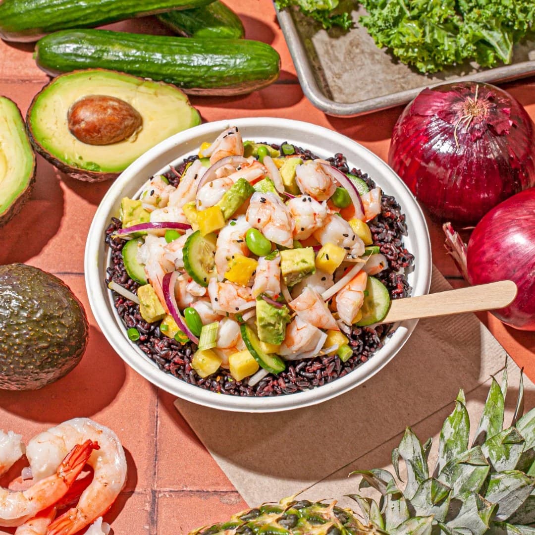 A Sweetfin poke bowl with shrimp, pineapple, avocado and red onion on black rice